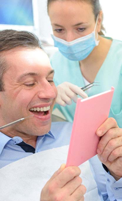 patient looking at smile after getting dental bridge in Denver
