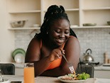 Woman smiling while eating healthy meal at home