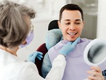 Man smiling at reflection in mirror with dentist